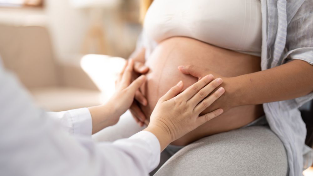 Pregnant Woman Gently Touching Her Belly During Prenatal Care - DR. PRIYANKUR ROY Blog